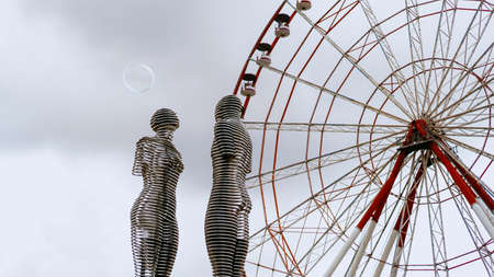 Batumi, Georgia - August, 2019 Moving metal sculpture Ali and Nino by Tamara Kvesitadze and Ferris wheelの写真素材