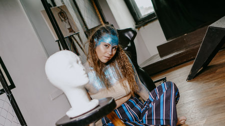 Artist in workshop. Woman with blue sparkles on her face. The concept of freaks and creative people....