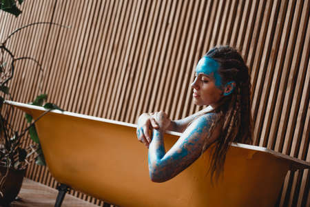 Portrait of beautiful woman with blue sparkles on her face in the bath. The concept of Individualityの写真素材