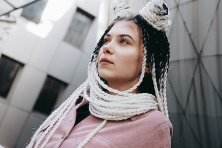 Young woman with futuristic looks. Girl with black and white dreadlocks or pigtails. Against the...