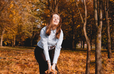 Woman throwing yellow leaves in the air - autumn parkの写真素材