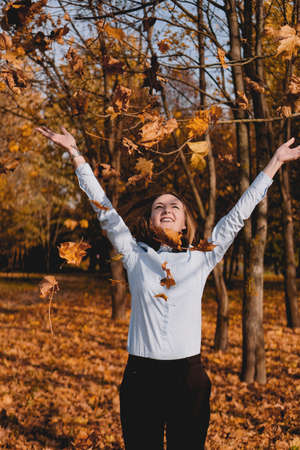 Woman throwing yellow leaves in the air - autumn parkの写真素材