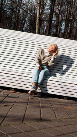 Pretty woman in sunglasses on bench at autumn park alone, lifestyle people conceptの写真素材
