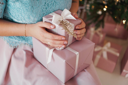 Hands holding gift present. Closeup of Female hands giving the gift in the New Year interior