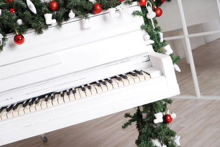 Keys on white upright piano with christmas decor with red ballsの写真素材