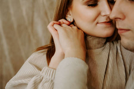 Close-up portrait of a beautiful young kissing couple in bed at home. Soft colorsの写真素材