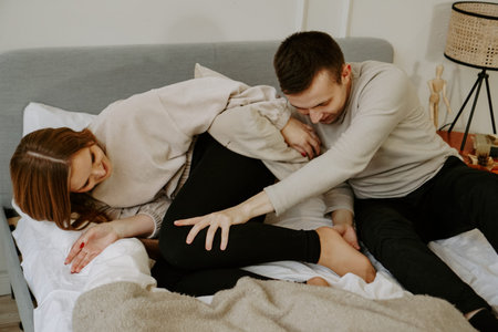 Young happy couple in love is lying in bed, smiling and fooling around. Soft colors