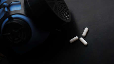 Epidemic and virus concept - white pills and Respirator on black backgroundの写真素材