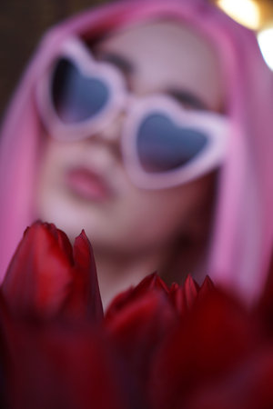 Out of focus, blurred background. Portrait of a dreamy girl with bright pink hair with flowers close...