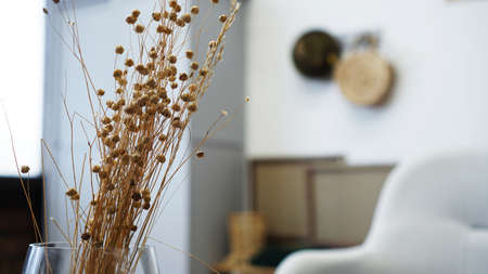 A vase with dry flowers on a table. Scandinavian classic room with wooden and white details, minimalistic interior design. Real photo. Cosy home.の写真素材