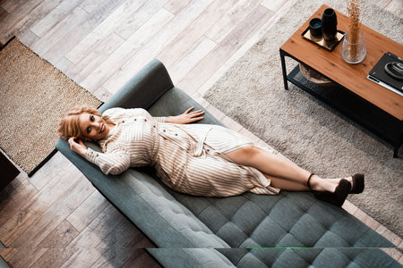 Top view of a smiling young woman relaxing on sofa at weekend an home
