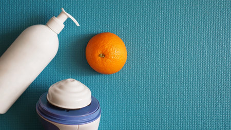 Electric massager for cellulite. Lotion, orange and anti-cellulite massage massager on a blue...