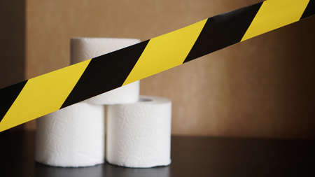 Stop panic - coronavirus. Rolls of Toilet paper behind the yellow tapeの写真素材