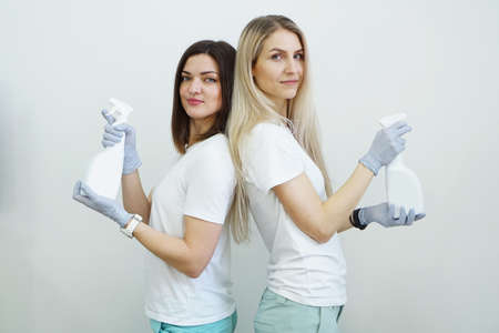 Two women hold spray bottle with antiseptic or detergent like guns. Health or cleaning concept Covid-2019の写真素材