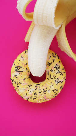 Sweet donut and banana on pink color background. Sex and Erotic conceptの写真素材