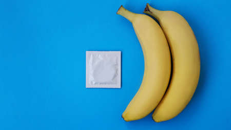 Condoms and two bananas together on blue background, the concept of contraceptives and the prevention of venereal diseases of same-sex marriage.の写真素材