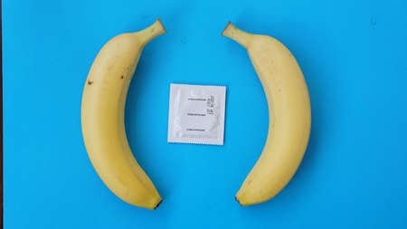 Condoms and two bananas together on blue background, the concept of contraceptives and the prevention of venereal diseases of same-sex marriage.の写真素材