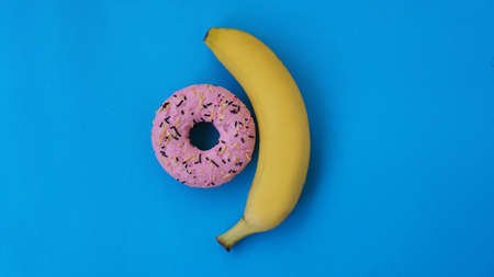 Sweet donut and banana on blue color background. Sex and Erotic conceptの写真素材