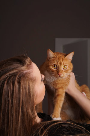 Beautiful young woman with a fluffy red cat on hand