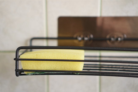 Sponge for washing dishes on metal shelf in kitchen. Concept of cleaning. Close-up interior. No people.の写真素材