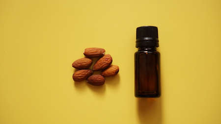 Bottle of almond oil and almonds on yellow background - Bottle and handful of nutsBottle and handful of nutsの写真素材
