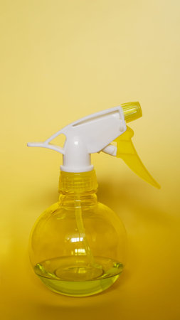 Spray bottle on yellow background. Portable pressure water sprayer pump. Sprayer bottle - vertical...