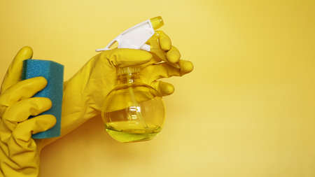 Hand in a rubber glove holds a cleaning sponge on a yellow background. Cleaning concept, cleaning service. Banner with bottle, sprays spongeの写真素材