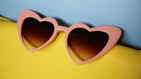 Yellow bag and heart-shaped sunglasses on blue background - summer pictureの写真素材