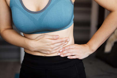 Close up of the woman holding her belly. Pain after home workout. Weight loss, slim body, healthy conceptの写真素材