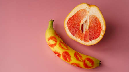 Composition with fresh banana with traces of red lipstick and grapefruit on pink background. Sex conceptの写真素材