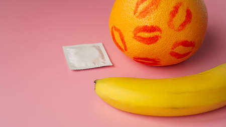Banana and grapefruit with condom on pink background. Safe Sex Conceptの写真素材