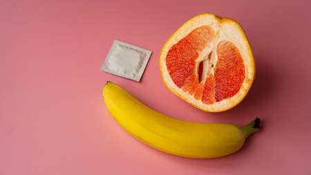Banana and grapefruit with condom on pink background. Safe Sex Conceptの写真素材