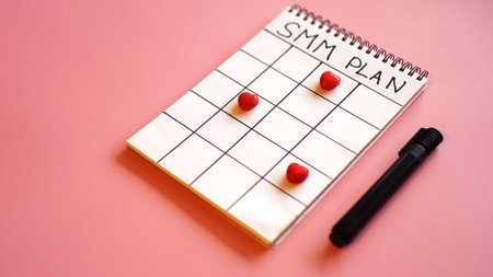 Social media marketing concept - SMM plan in a notebook on a pink background with candy in the form...