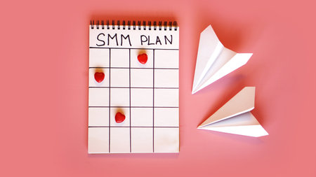 Social media marketing concept - SMM plan in a notebook on a pink background with candy in the form...