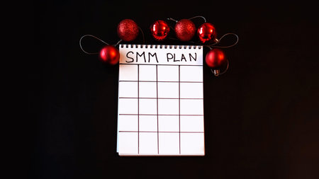 Freelance project. SMM plan blank. White sheet on a black festive background with red Christmas...