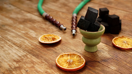 Coals for hookah on wooden background with dry oranges and bowl. Place for textの写真素材