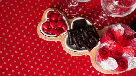 Chocolates and sweets on heart-shaped plates. Festive table setting for date of lovers. Red backgroundの写真素材