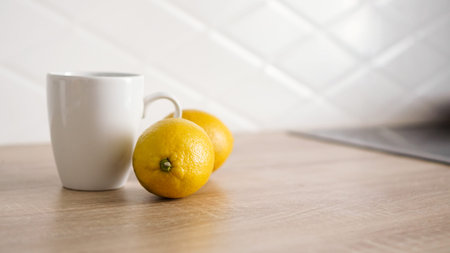Two lemons on the kitchen table near a white mug of tea. Morning conceptの写真素材