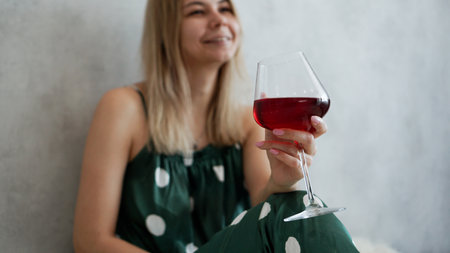 Girl in green pajamas in bed with a glass of red wine. Morning wine in bedの写真素材