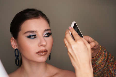 Make up artist taking mobile photo for the model with blue fashion makeupの写真素材