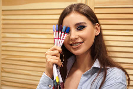 Beautiful girl with blue makeup covers her face with a palette with nails for manicureの写真素材