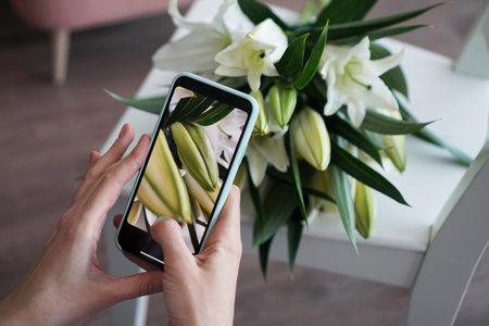 The girl makes a photo on the phone. Photographs a bouquet of white lilies. Mobile photography...