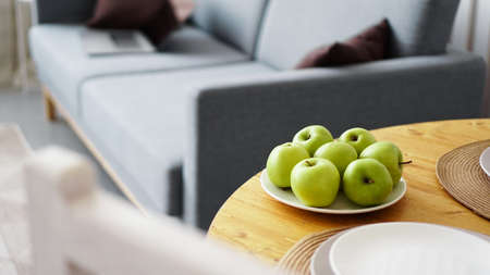 Green apples on a white plate on a wooden table. White modern scandinavian interiorの写真素材