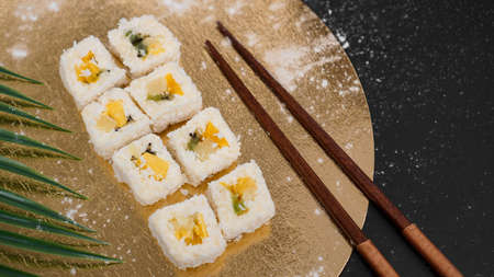 Dessert Sushi - Roll with Various Fruit and Cream Cheese inside. On a gold background and with a tropical leafの写真素材