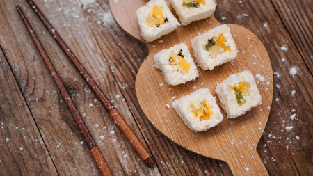 Sushi delivery. Sweet rolls made from rice, pineapple, kiwi and mango. Rolls on a wooden background....