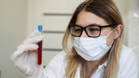 Female scientist holding test tube with blood sample. The concept of analyzes and diagnostics of...