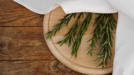 Sprigs of rosemary on a wooden board for cutting. Rustic style. Spiceの写真素材