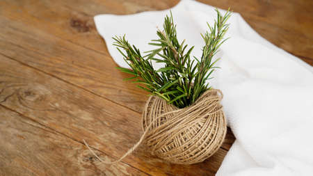 Sprigs of rosemary and skeins of jute rope on a wooden board for cutting. Rustic style. Spiceの写真素材