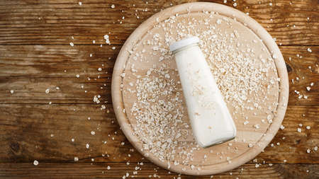 Oat flakes and bottle of fresh milk on a wooden boardの写真素材