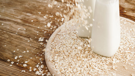 Oat flakes and bottle of fresh milk on a wooden board